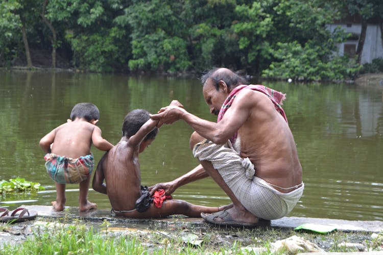 Man Cleaning Boy By River