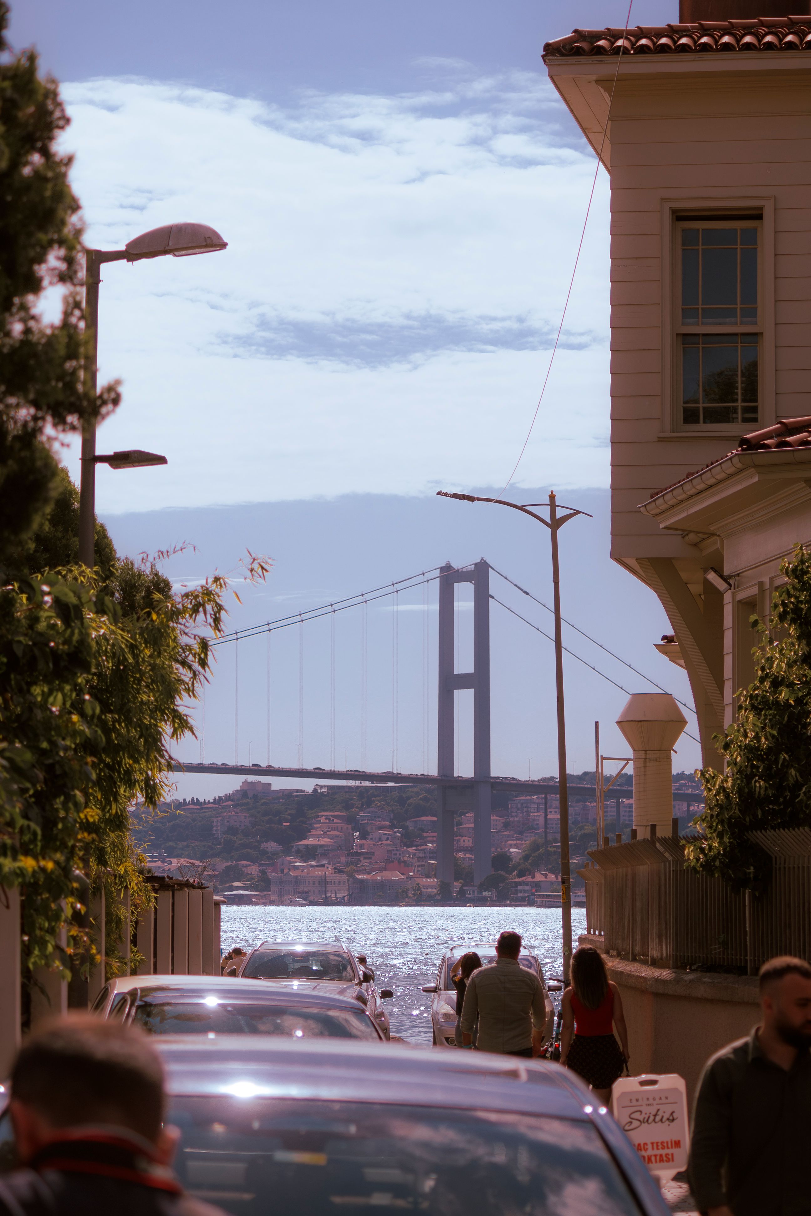 Street view in Istanbul showcasing the Bosphorus Bridge in the background with people and traffic.