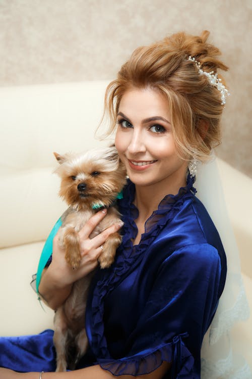 Beautiful Woman Sitting on a Sofa and Holding a Dog 