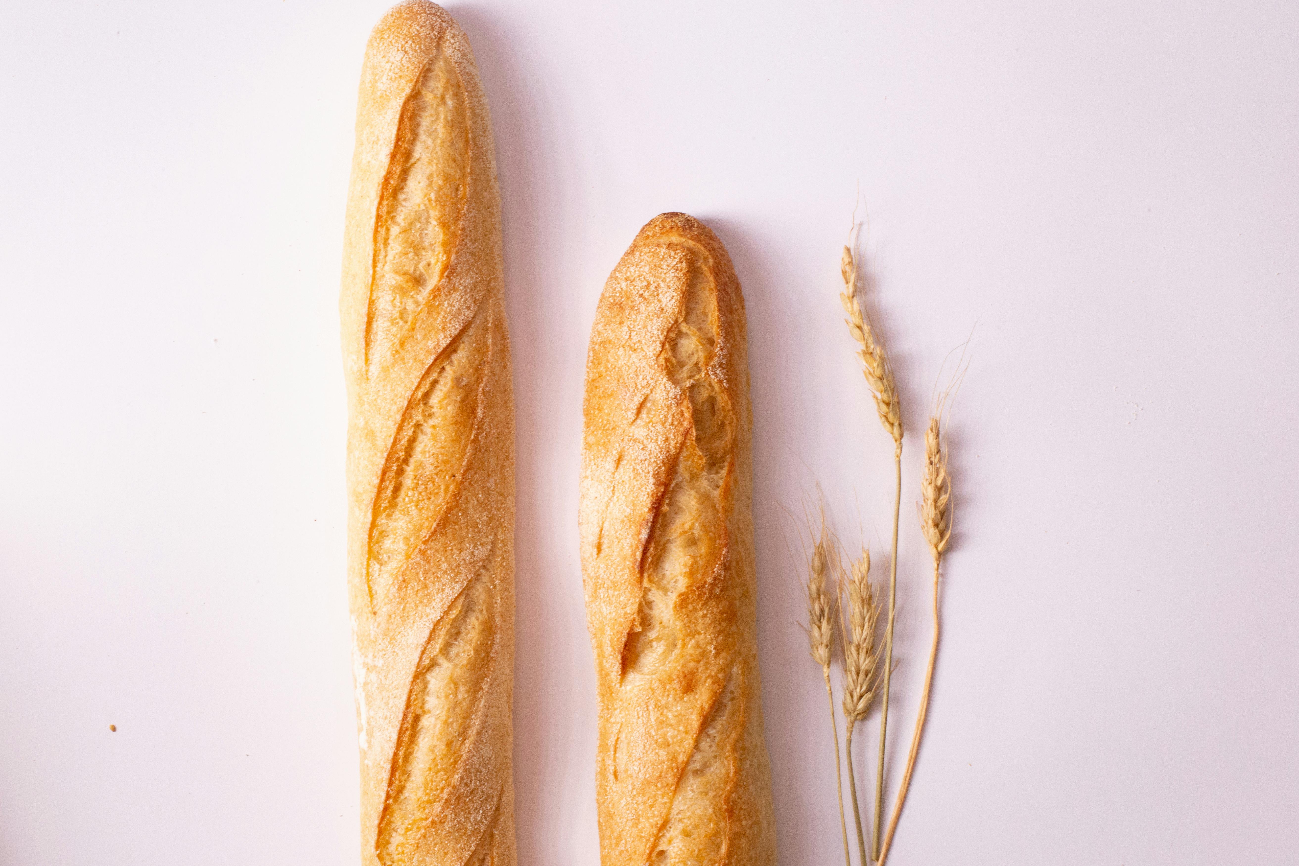 Small french baguette isolated on light background. Stock Photo by