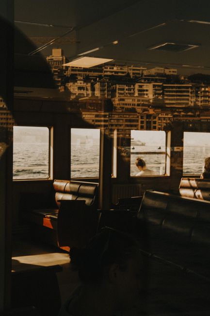 A cityscape reflecting off ferry windows, creating a double exposure effect.