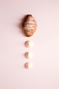 在柔软的粉红色背景下，羊角面包和奶油优雅地展示着