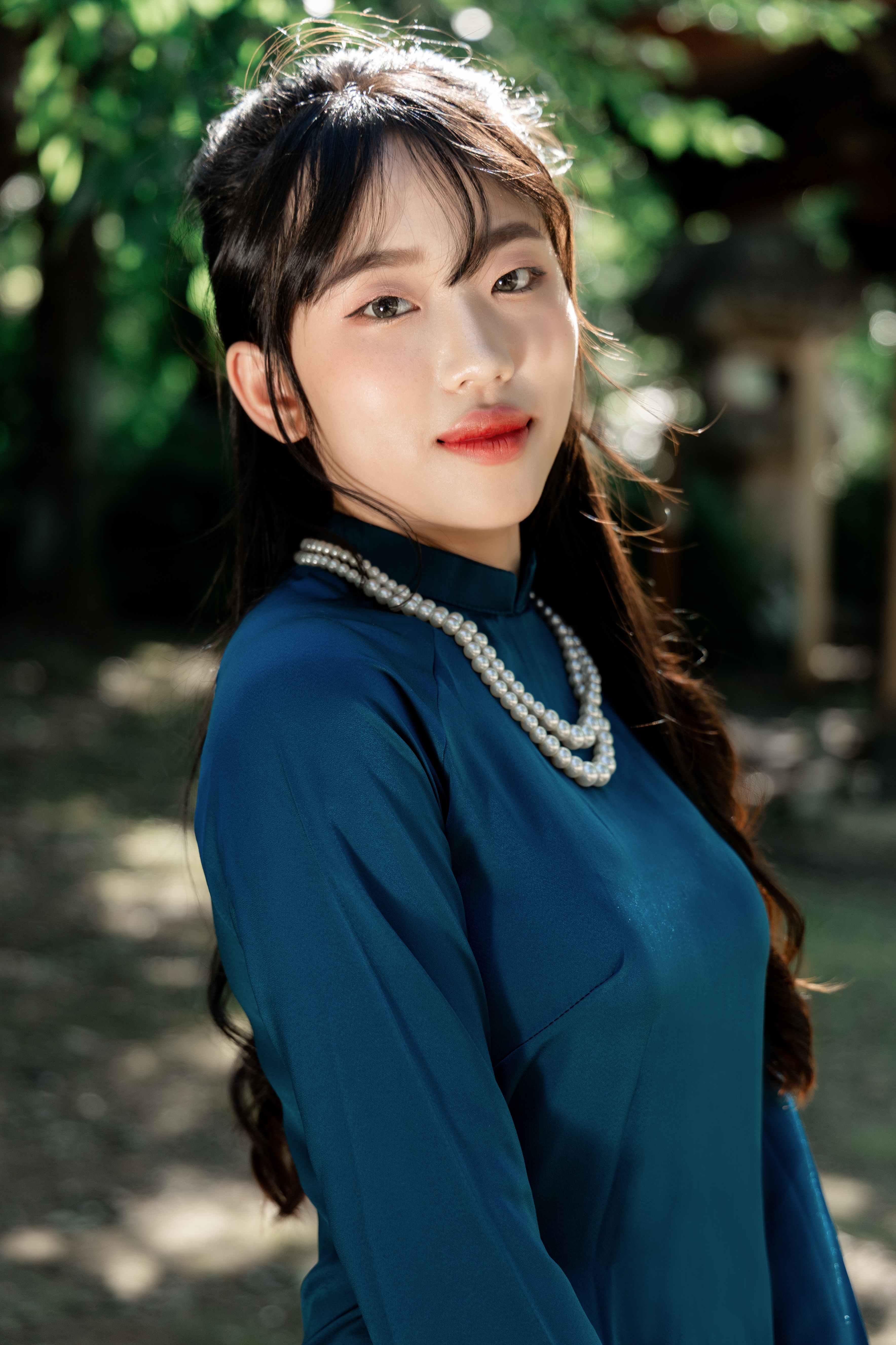 Elegant portrait of a woman in a blue dress and pearls, captured outdoors in Tokyo, Japan.