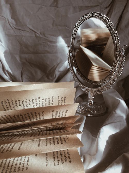 Free Vintage book pages reflected in an ornate mirror on a crumpled fabric background. Stock Photo