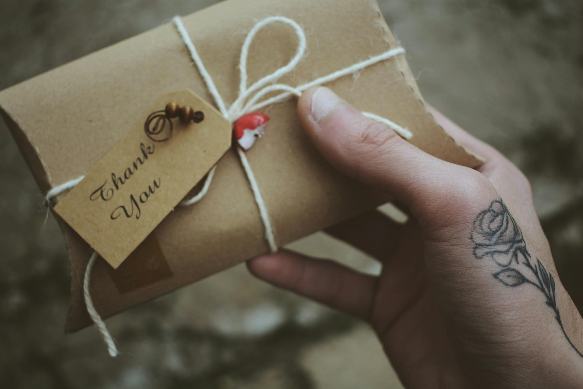 Image of a hand holding a letter with the words 'thank you.' This reminds us to practice gratitude around the joyful experiences we've had with love and dating so we don't want to give up. 
