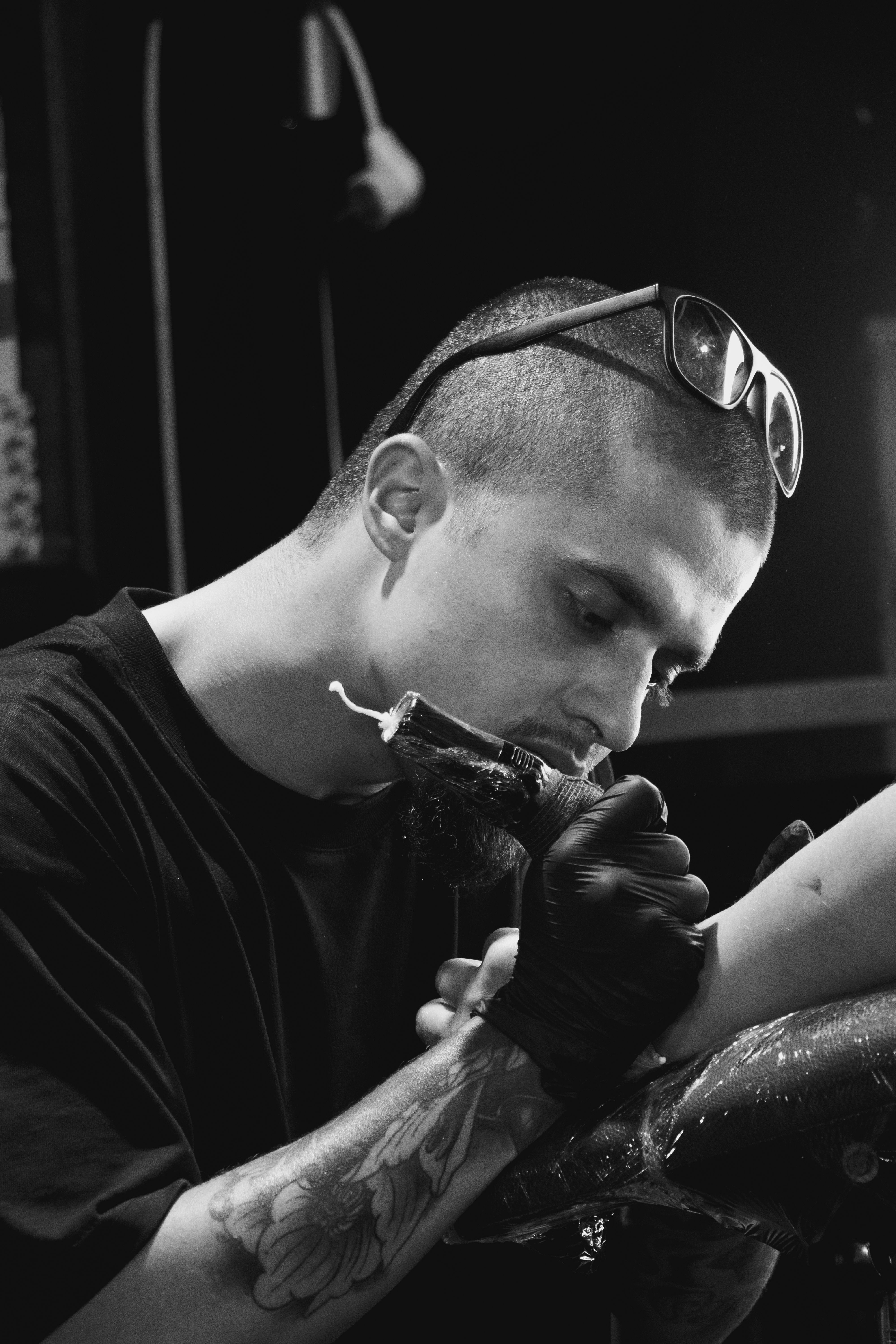 Close-up of a tattoo artist concentrating on creating an intricate design in a studio setting.