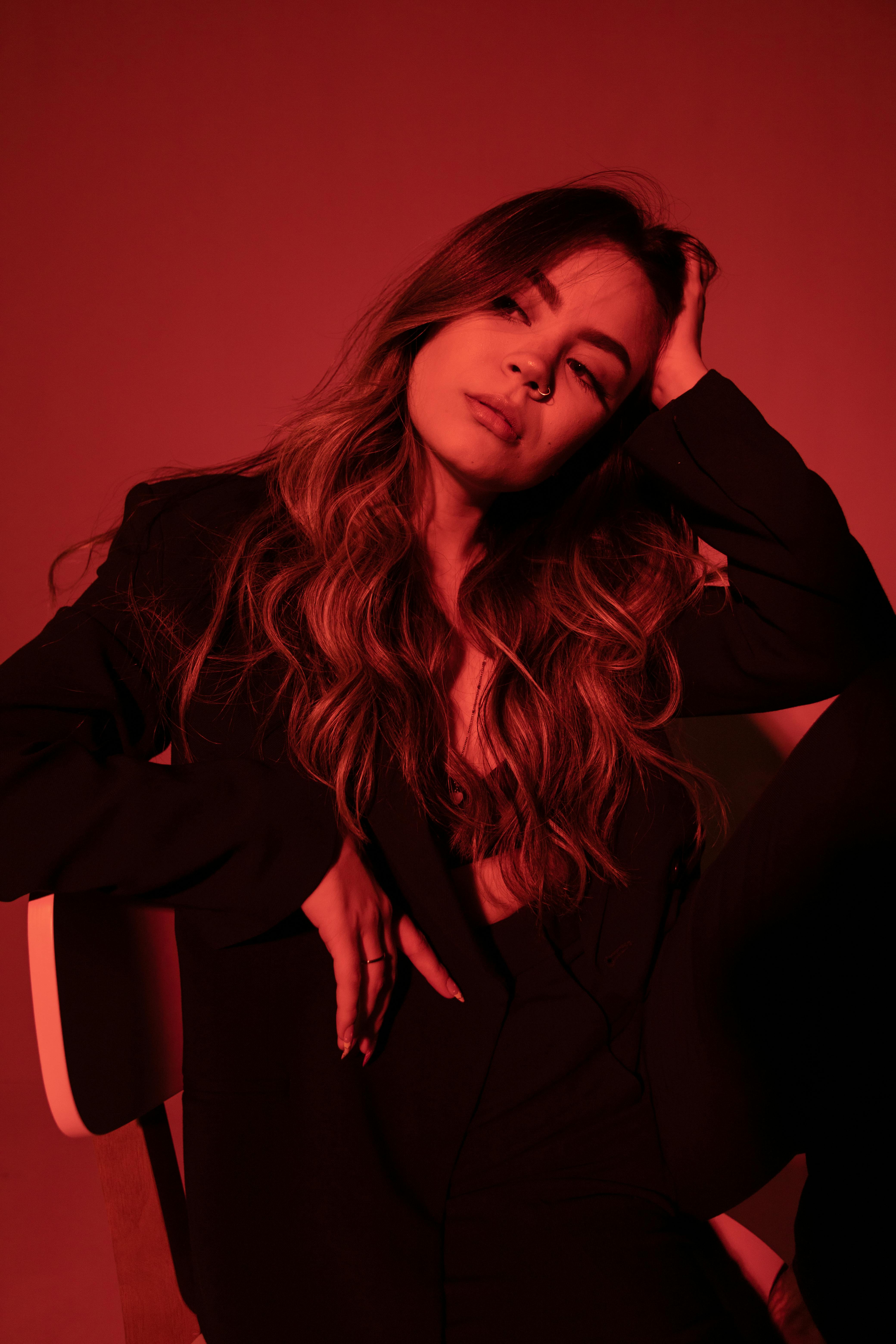 Fashion portrait of a woman in black attire under dramatic red lighting.