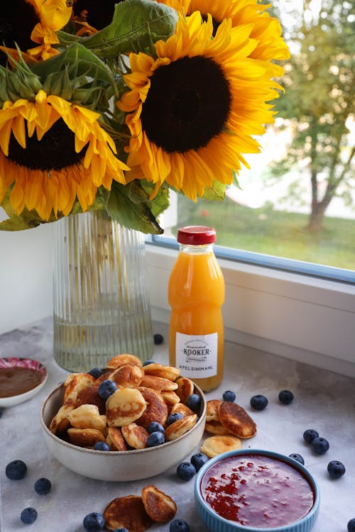 Pancakes and Fruit near Juice and Sunflowers