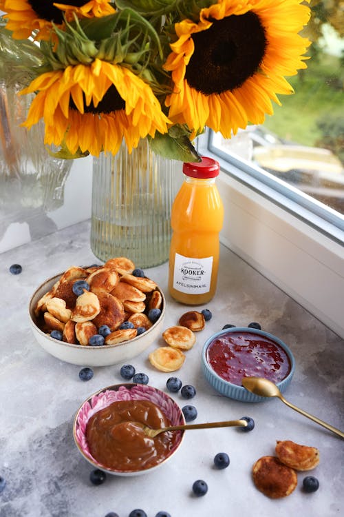 Pancakes with Blueberries near Sunflowers and Fruit Juice