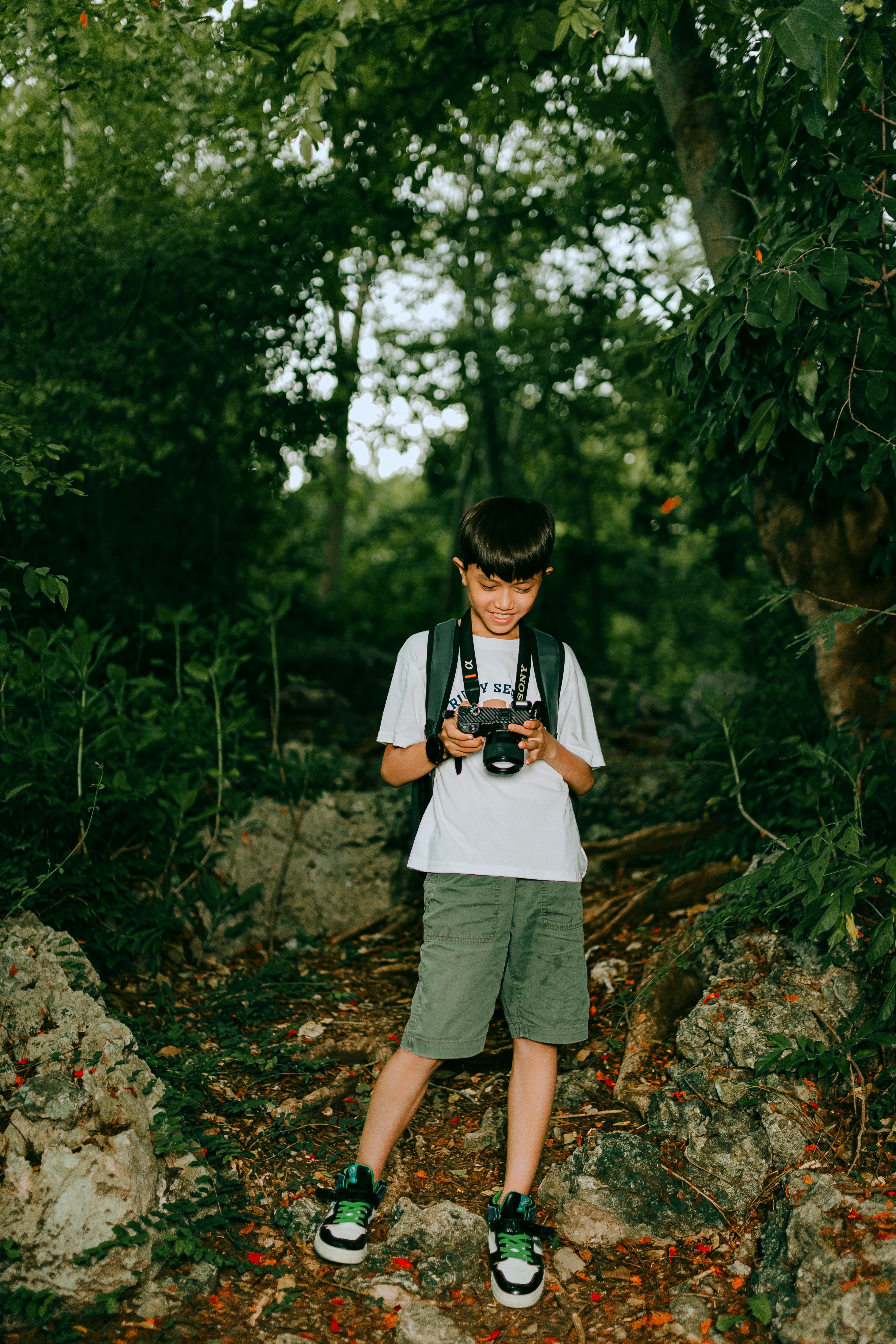 a young boy with a camera in the woods