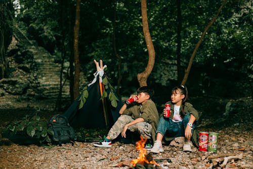 Boy and Girl Camping by the Fire in a Forest 