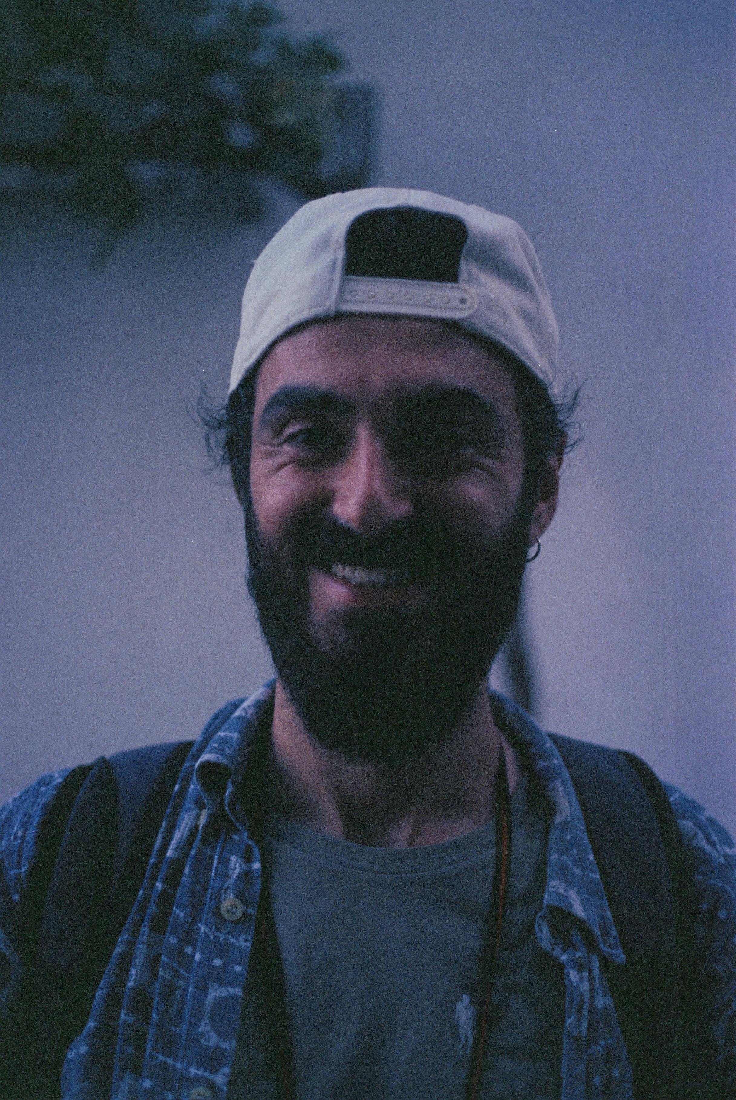 Casual outdoor portrait of a smiling bearded man wearing a cap in Bursa, Türkiye.