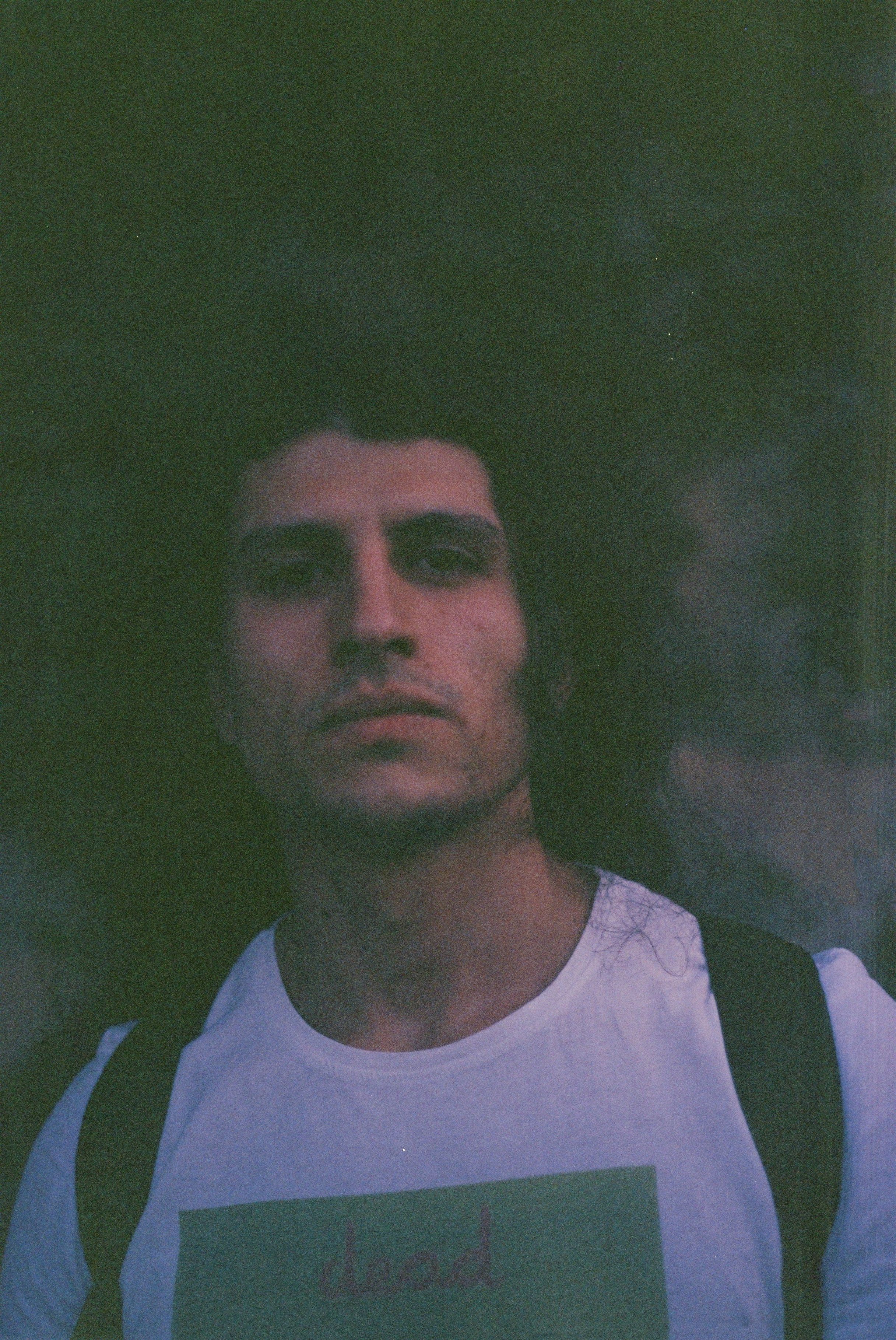 Pensive young man outdoors in dim light with a vintage style.
