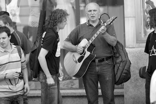 A Man Playing a Guitar on a Street in City 