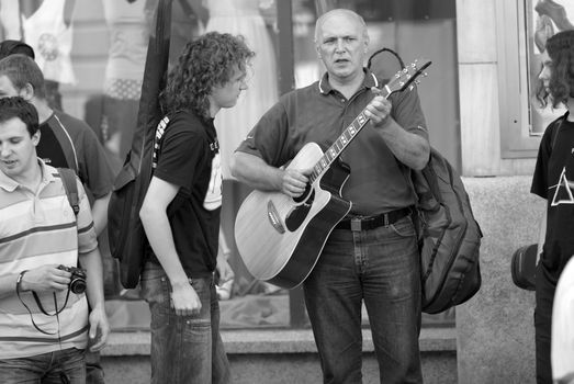 A man playing guitar while standing next to people