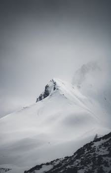 Snowy mountain peak shrouded in mist, creating a mysterious winter scene in Hintertux, Austria.