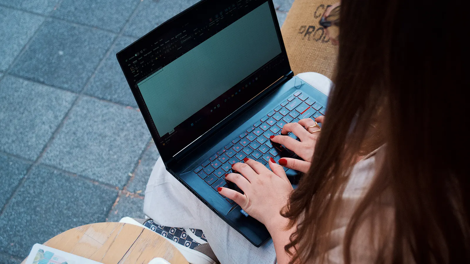 Woman typing on a laptop at a cafe table replying to messages