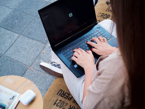 A young woman using a laptop outdoors, showcasing mobility and technology in action.
