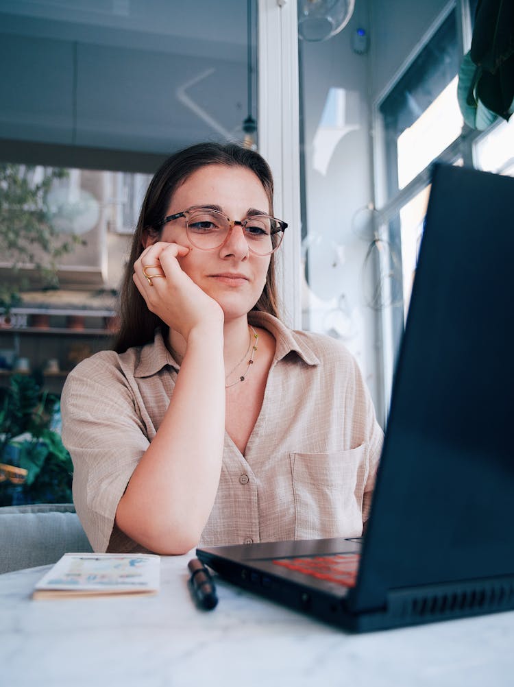 Young Woman Sitting At The Table In A Cafe And Using A Laptop