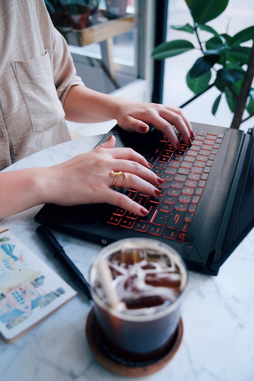 Close-up of a Woman Sitting at the Table in a Cafe and Using a Laptop