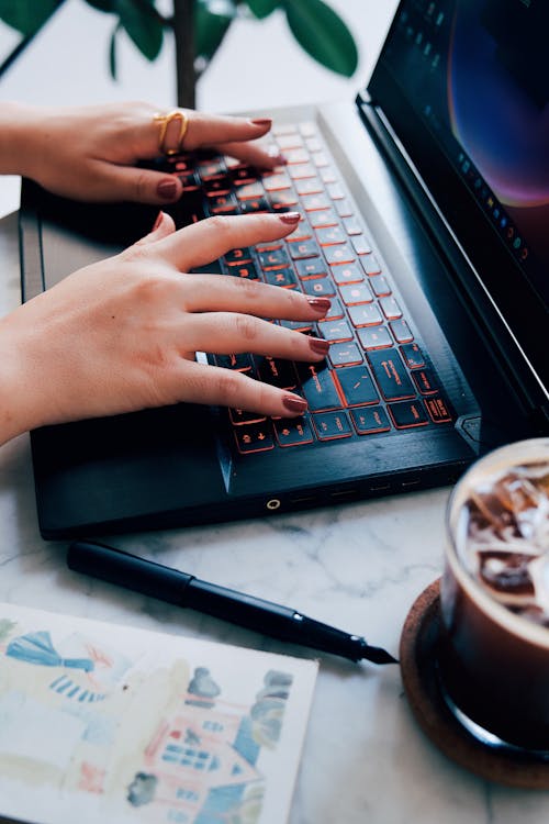 Close-up of a Woman Sitting at the Table in a Cafe and Using a Laptop