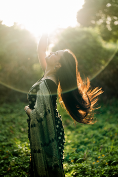 A woman in a saree enjoying a sunny day outdoors, exuding joy and freedom.