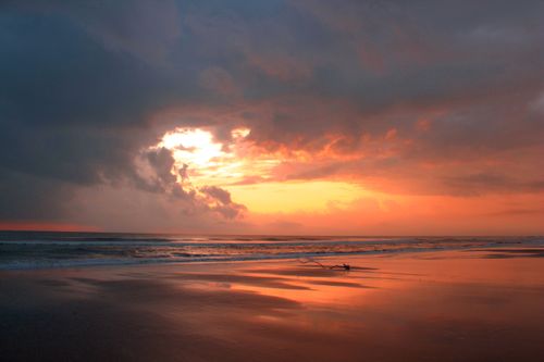 Free Dramatic sunset over Guaratuba beach with reflections on wet sand and vibrant sky. Stock Photo