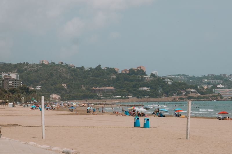 Crowded sandy beach in Benidorm with scenic hills and clear blue waters