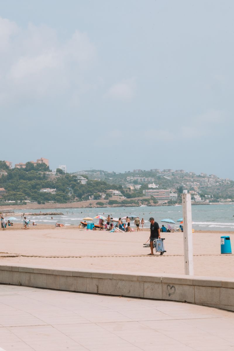 Tourists enjoying a sunny beach in Benidorm with clear blue skies