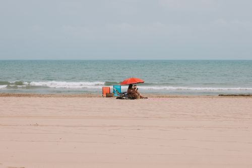 Free Sunbathing under an umbrella on the sandy beach of Benidorm, Spain. Stock Photo