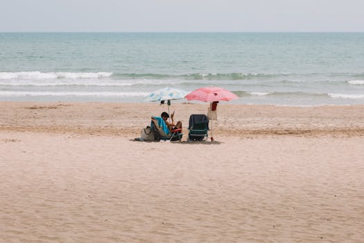 A peaceful day at the sandy beach in Benidorm, Spain with umbrellas and sunbeds by the shore.