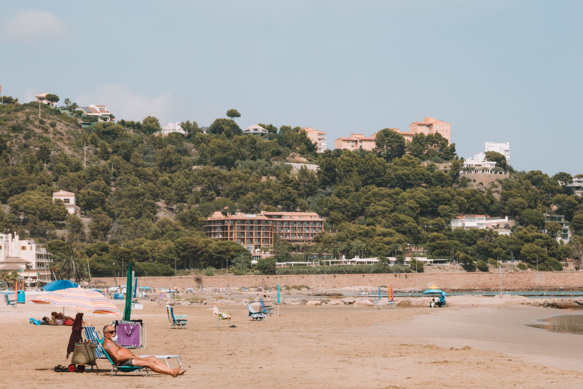 Sunny beach day in Benidorm, Spain with scenic hills and leisure activities.