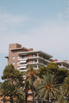 Modern resort building surrounded by lush palm trees under a clear blue sky in Benidorm, Spain.
