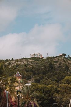 Beautiful view of a villa on a lush hillside with palm trees in Benidorm, Spain.