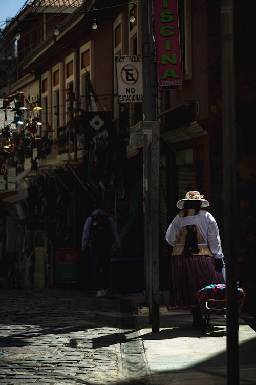 Back of a Woman Walking with a Cart along a Sidewalk