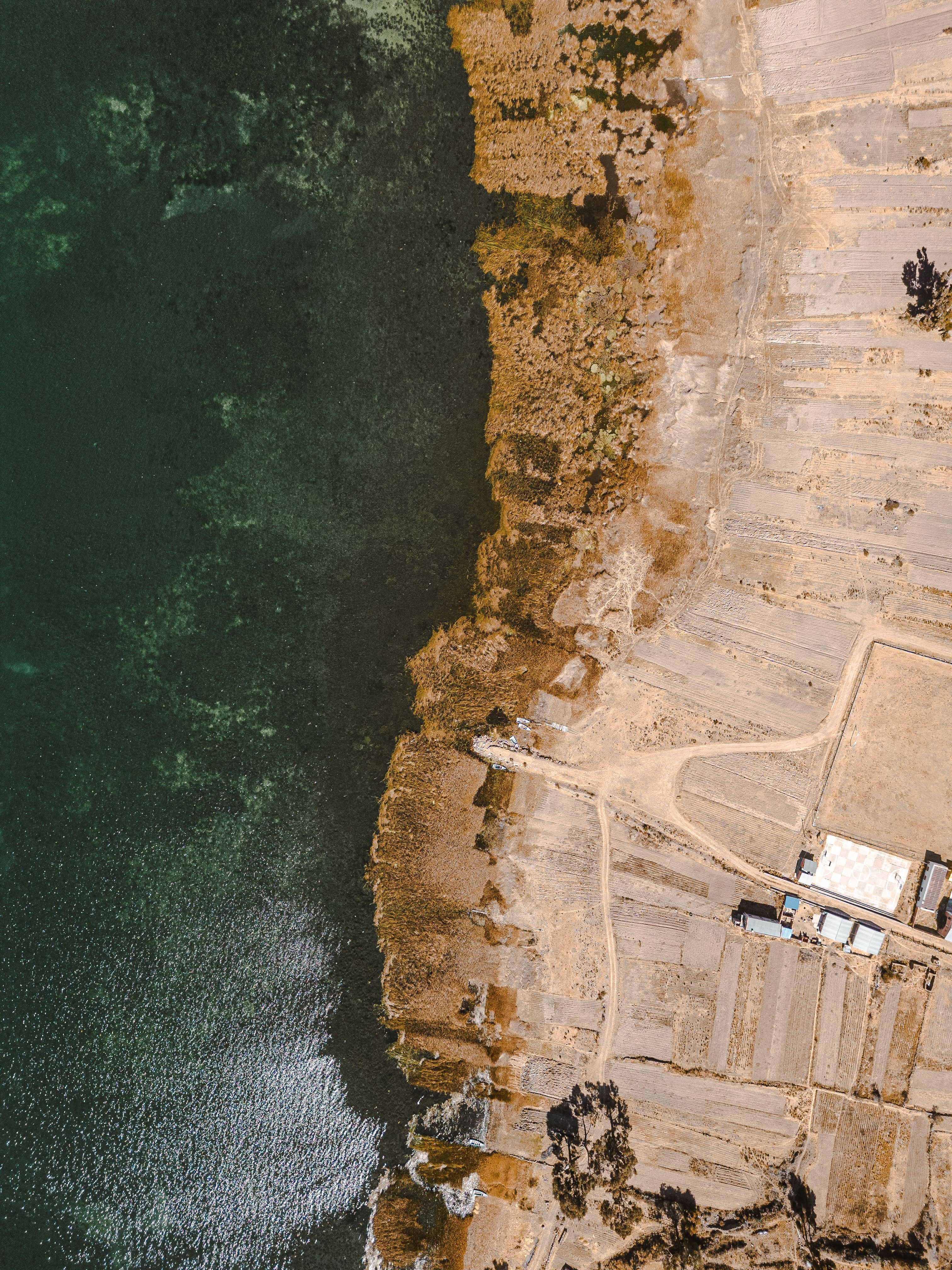 Aerial shot of the shoreline in San Pablo De Tiquina, Bolivia, showing lake and rural landscape.
