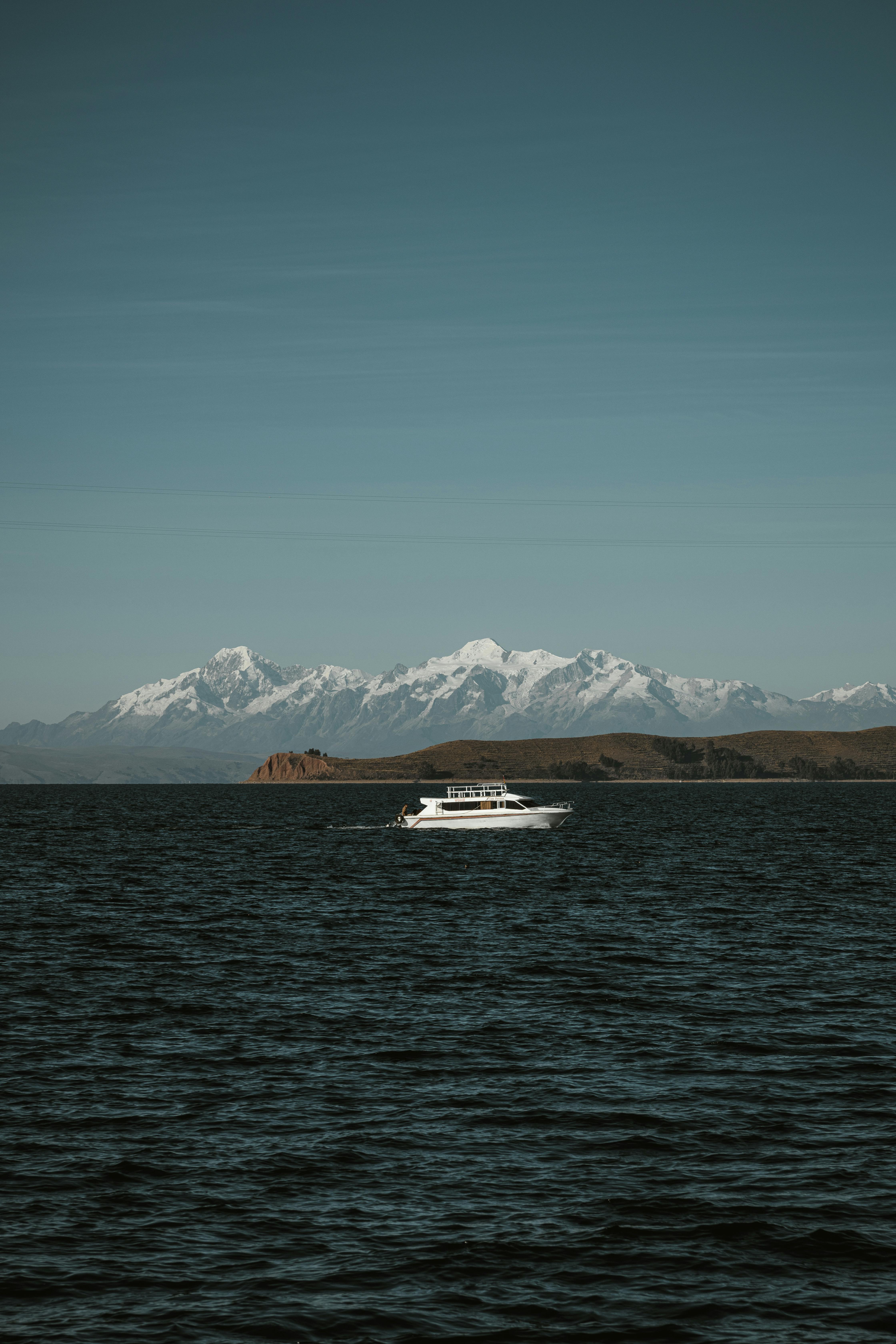 A tranquil yacht journey with stunning views of snow-capped mountains across a peaceful sea.