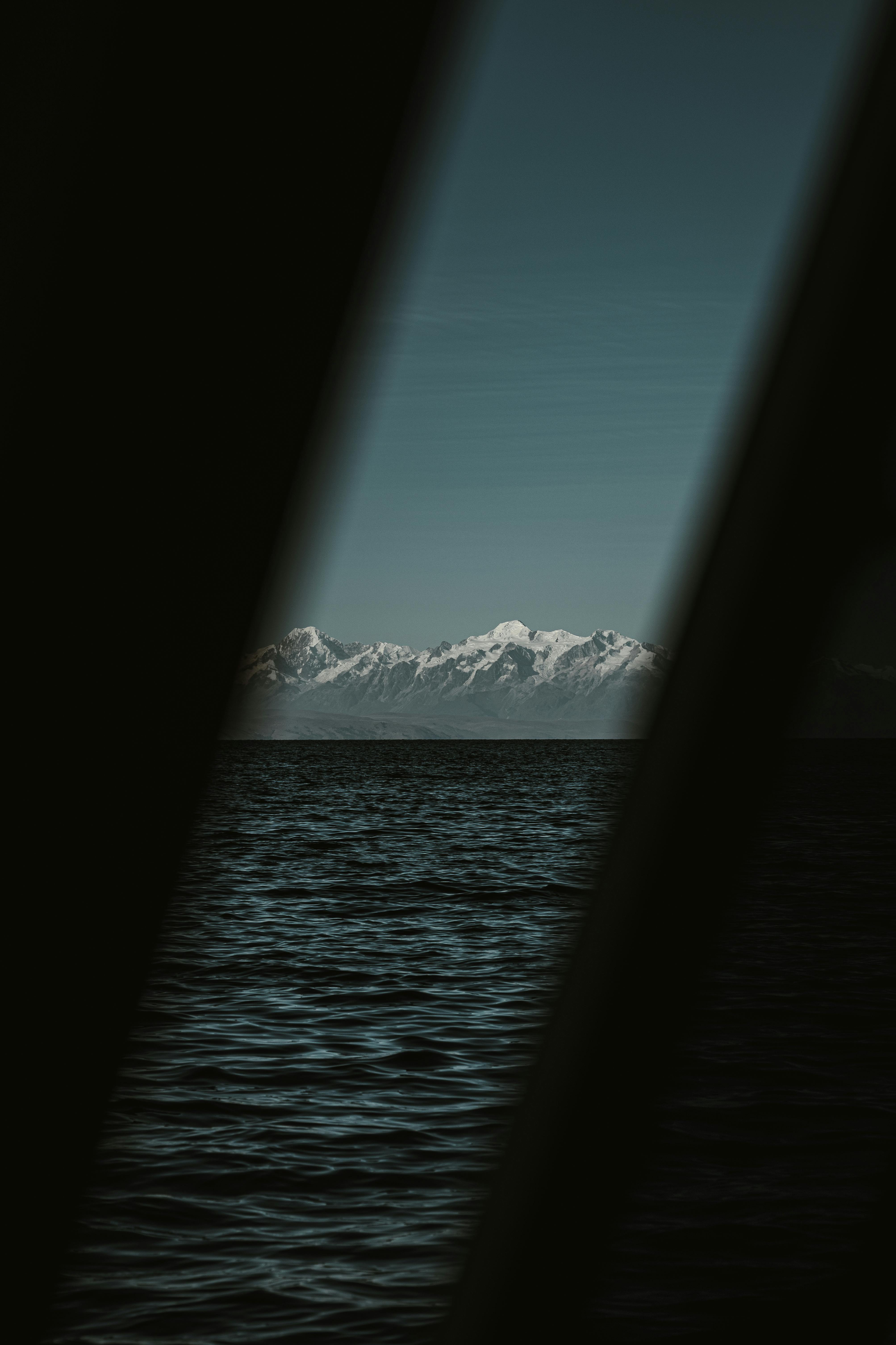 Peaceful ocean scene with stunning snow-covered mountains under a clear blue sky.