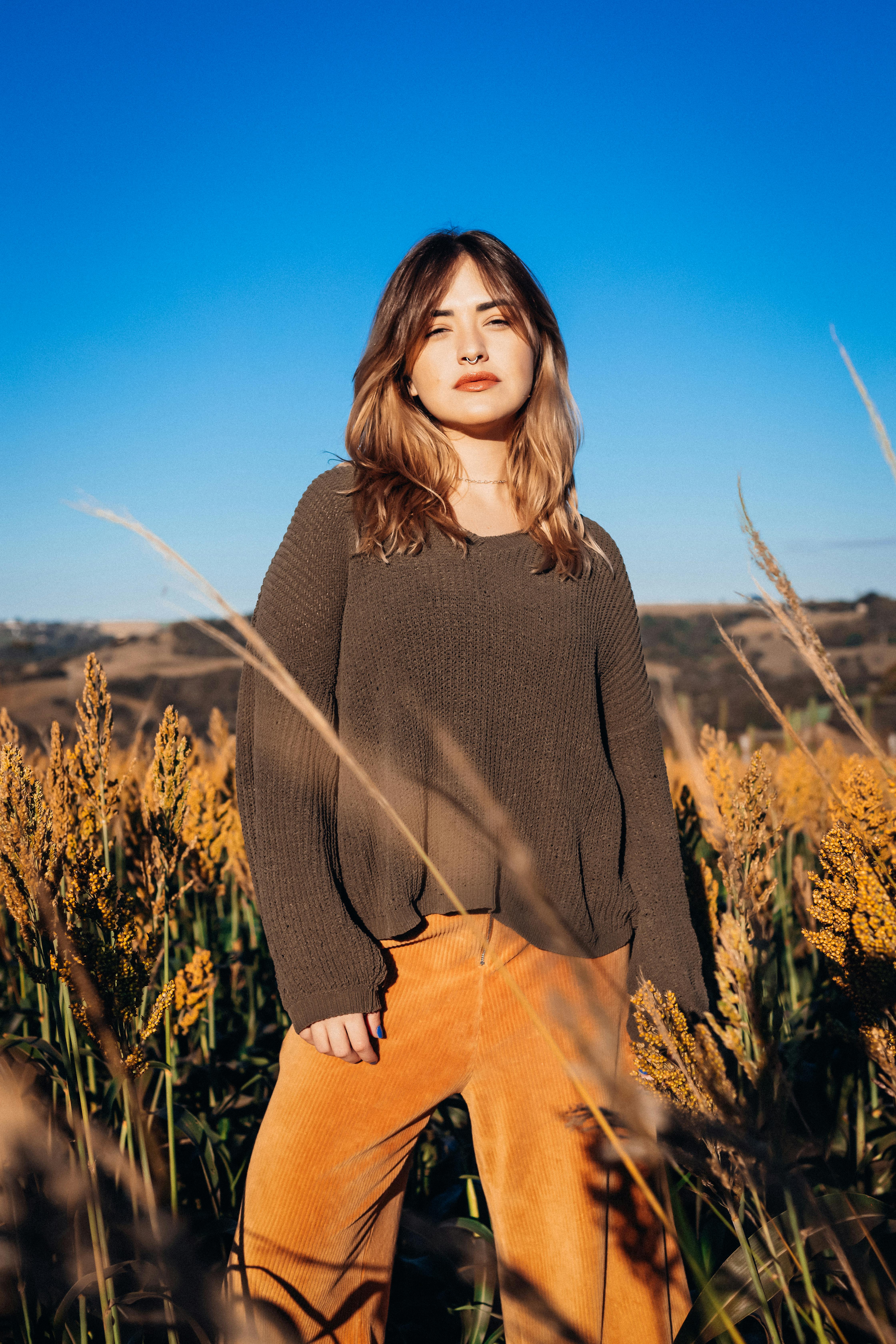 Portrait of a woman standing in a sunlit meadow in PR, Brazil, depicting fashion and nature.