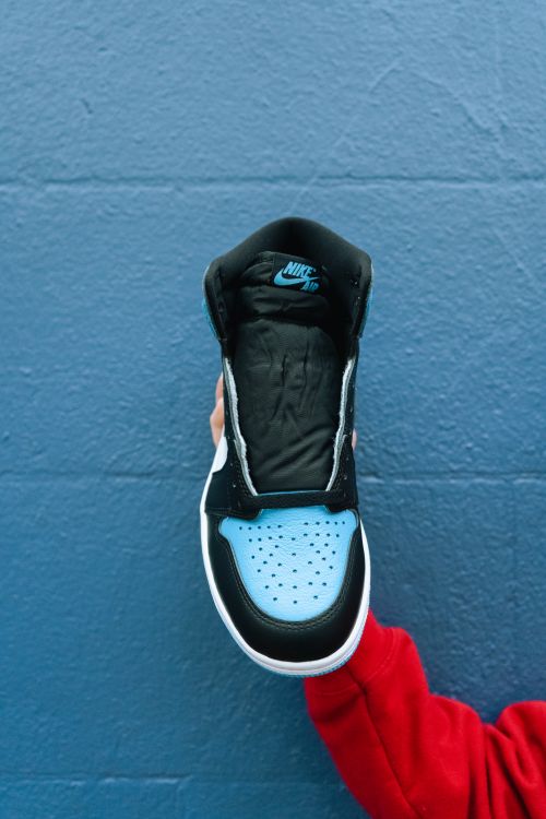 Free A modern Air Jordan 1 sneaker held against a textured blue wall, showcasing style and fashion. Stock Photo