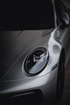 A detailed close-up of a silver sports car's headlight, showcasing its sleek design.