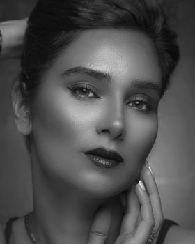 A close-up black and white portrait of a woman with elegant makeup and hairstyle.