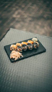 Close-up of sushi rolls on a slate plate served outdoors.