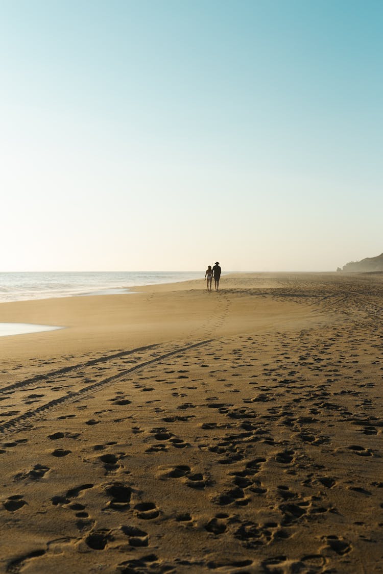 People Walking On Beach At Sunset