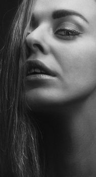 Close-up black and white portrait of a woman with dramatic lighting and expression.