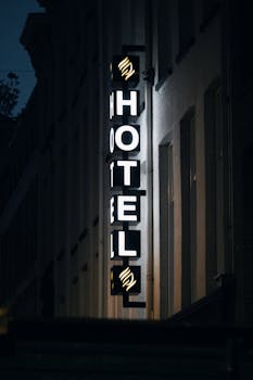 Neon hotel sign glowing brightly on an Amsterdam street at night, showcasing urban nightlife.