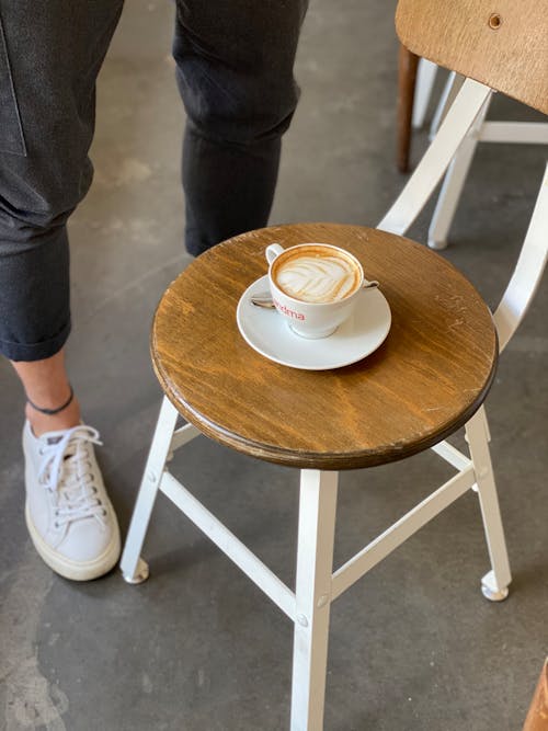 Man Standing next to a Chair with a Cappuccino 
