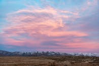 白雪皑皑的山脉上，日落令人惊叹，云层充满活力，地平线广阔