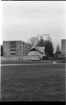 Monochrome image of a residential area with buildings and grass field.