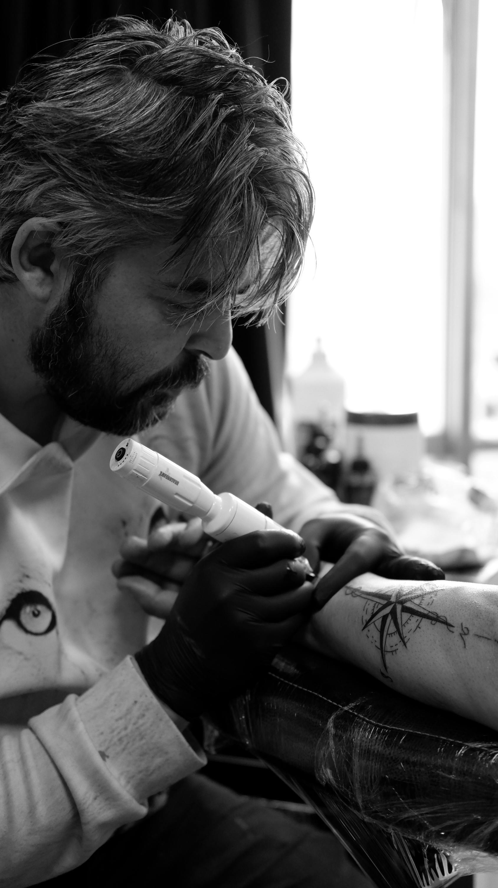 Tattoo artist working meticulously on a design in Ankara studio.